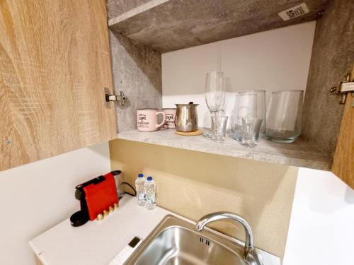 a kitchen counter with a sink and glasses on a shelf at Rhodes Port Stories in Rhodes Town