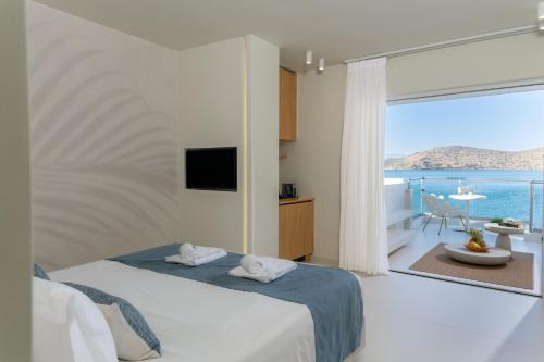 a bedroom with a bed with a view of the ocean at Elounda Akti Olous (Adults Only) in Elounda