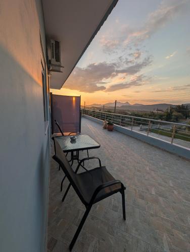 a table and a chair on a balcony with the sunset at Pame Apartments Only Adults in Valanidorachi