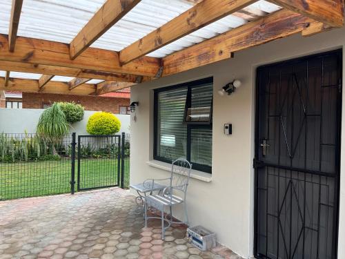 a patio with a wooden pergola and a chair at 22 on Port Natal Hartenbos in Hartenbos