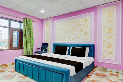 a bedroom with a blue bed with pink walls at Collection O Airport Road Solina in Srinagar