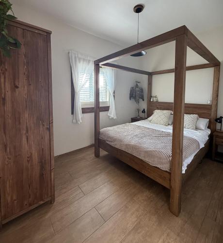 a bedroom with a wooden canopy bed and a window at Avtalyon Wood accommodation in Avtalyon