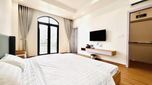 a white bedroom with a bed and a tv at Anna Belle Đồi Rồng Hotel - Homestay chuỗi HPT Home Hải Phòng in Kon Rung (1)