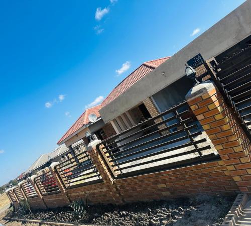 a brick house with a fence on the side of it at Knovi Guesthouse in Bulawayo