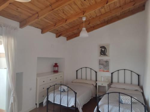 a bedroom with two beds and a wooden ceiling at Casa del Valle Encantado in Galaroza