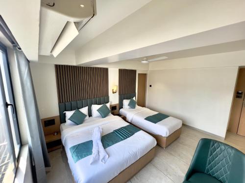 a hotel room with two beds and a chair at Hotel Comfort in Surat