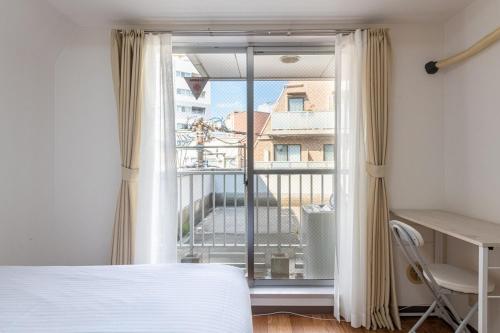 a bedroom with a bed and a view of a balcony at アスピア305 Easy access to Shinjuku 1-minute walk from Koshinzuka Station in Tokyo