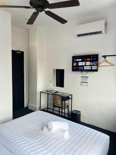 a bedroom with a bed with a ceiling fan and a table at Quee Hotel in George Town