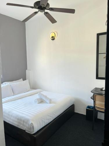 a bedroom with a bed with a ceiling fan at Quee Hotel in George Town