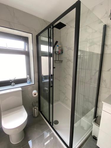 a bathroom with a toilet and a glass shower at Two double bedroom self contained Retreat in Thundersley