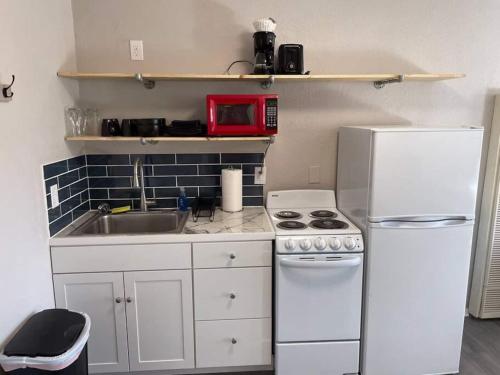 a small kitchen with a white refrigerator and a sink at Studio W Balcony - Near Nob Hill And Hospitals in Albuquerque