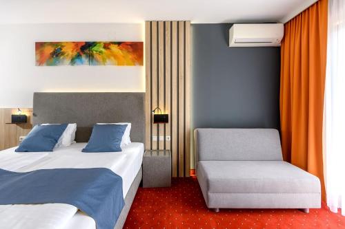 a hotel room with two beds and a chair at Vitalhotel Krainz in Loipersdorf bei Fürstenfeld