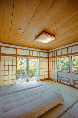a bedroom with a large bed in a room with windows at Guesthouse 湯本見山 in Hakone