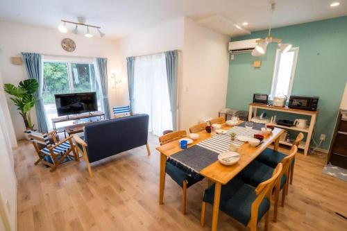 a living room with a wooden table and chairs at 家族の笑顔 笑顔があふれる体験を 沖縄一棟貸しのお宿 Coral Onnason in Onna