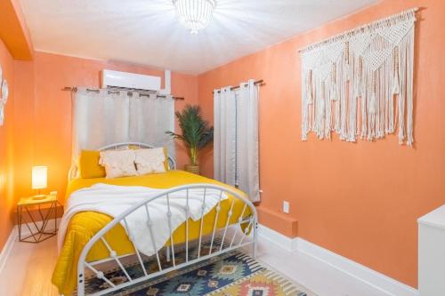 een slaapkamer met oranje muren en een geel en wit bed bij Funky Beach House Steps 2 Ocean Center & Beach in Daytona Beach