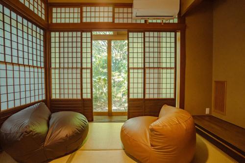 a room with a chair in a room with windows at Guesthouse 湯本見山 in Hakone