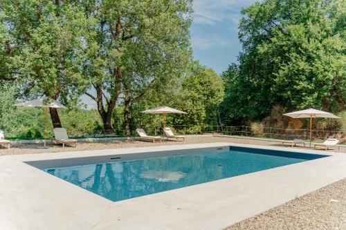 a swimming pool with two chairs and two umbrellas at Tenuta Alela in Figline Valdarno