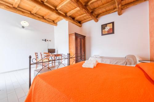 a bedroom with a bed with an orange blanket at Antico Casale Gioiosa Marea in Gioiosa Marea