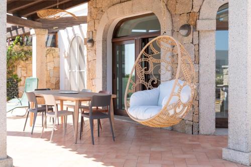 a patio with a wicker chair and a table at Villa Paradisu in Alghero