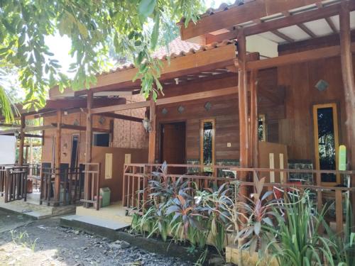 a wooden house with a porch and some plants at Pandan Arum Surfing in Pulau Lutung