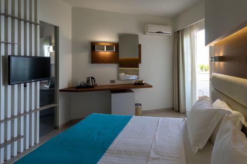 a hotel room with a bed and a television at Elounda Akti Olous (Adults Only) in Elounda