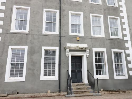 un edificio gris con ventanas blancas y una puerta en Lowther Apartment, en Whitehaven