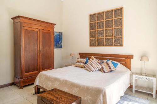 a bedroom with a bed and a wooden cabinet at Villa du Lagon, à 50m de la plage avec piscine privée in Roches Noires