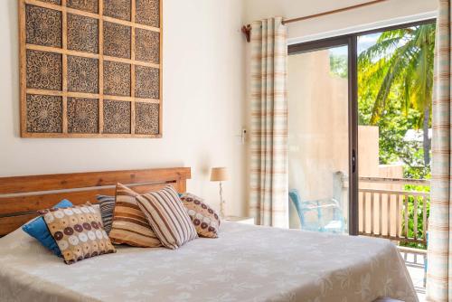 a bedroom with a bed with pillows and a balcony at Villa du Lagon, à 50m de la plage avec piscine privée in Roches Noires
