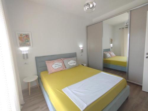 a bedroom with a yellow bed and a mirror at Super Leisure Vila-Plazhi San Pietro, Gjiri i Lalezit in Lalzit Bay