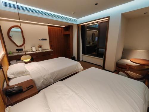 a hotel room with two beds and a mirror at Lushan Youlu Villa in Jiujiang