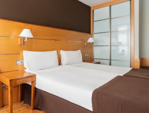 a bedroom with a large white bed and a table at Exe Las Palmas in Las Palmas de Gran Canaria