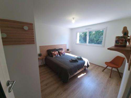 Un dormitorio con una cama y una ventana y una silla. en Maison Cosy T4 proche de la mer, en Saint-Brévin-lʼOcéan