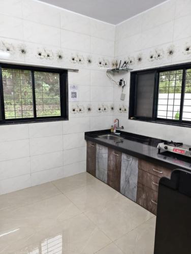 a kitchen with a sink and two windows at AM2PM Private Pool Villa in Badlapur