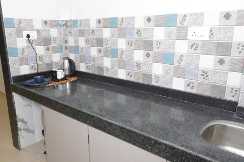 a kitchen counter with a sink and tiles on the wall at Hotel Sai Agastya Inn in Shirdi