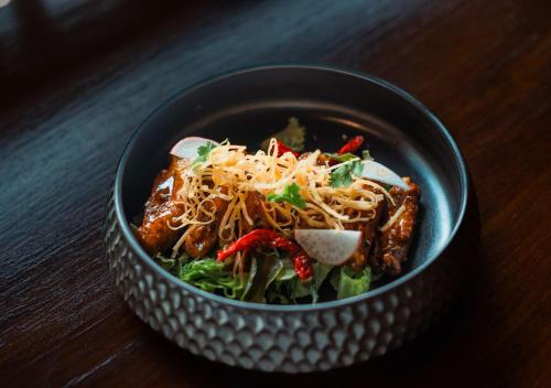 a bowl of food with noodles and vegetables on a table at Unagi Wooden Villas by Emana in Ubud