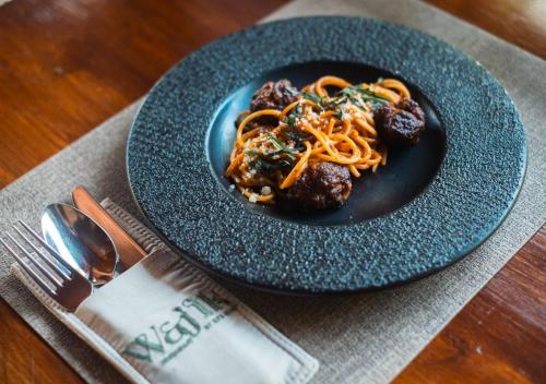 a plate of food with spaghetti and meatballs on a table at Unagi Wooden Villas by Emana in Ubud