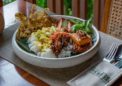 a bowl of food with rice and vegetables on a table at Unagi Wooden Villas by Emana in Ubud
