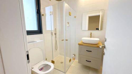 ein Badezimmer mit Dusche, Toilette und Waschbecken in der Unterkunft דירת פאר מול חוף הים in H̱adera