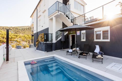 una casa con piscina al lado de un edificio en Beachfront Villa Marivi with Pool and Game Room, en Podglavica
