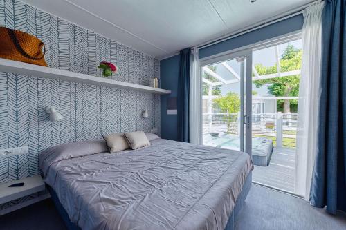 a bedroom with a bed and a sliding glass door at San Benedetto Camping Relais in Peschiera del Garda