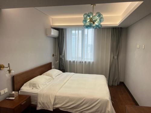 a bedroom with a white bed and a ceiling fan at Guangyao Service Apartment Beijing Ritan in Beijing