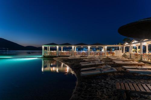 a resort with a row of lounge chairs in the water at night at Elounda Akti Olous (Adults Only) in Elounda