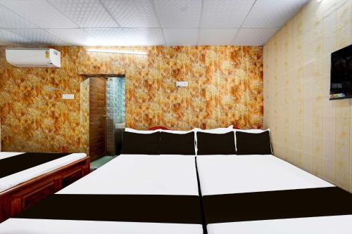 a bedroom with two beds and a wall with orange wallpaper at Collection O Vadapalani Metro Station Vishnu's Galaxy Rooms in Chennai