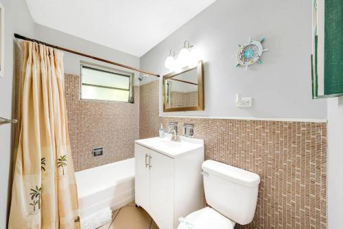 a bathroom with a toilet and a sink and a tub at Beach Apart By Pmi Unit 3 in West Palm Beach