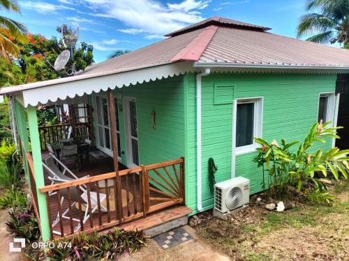 a green tiny house with a porch at Gîte le Colibri, Bouillante - Plage de petite Anse in Bouillante