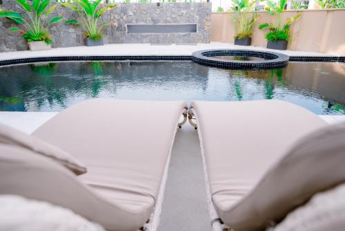 a pool with two lounge chairs in front of a swimming pool at Regal Victoria Luxury Pool Villa in Dien Ban