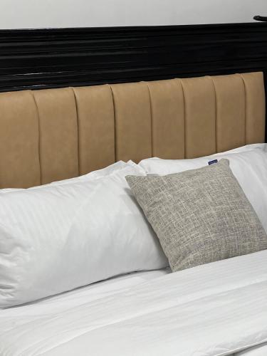 a bed with white pillows and a brown headboard at Ohana studio homes in Nairobi