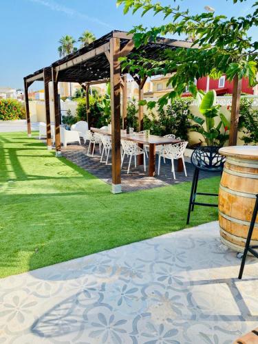 a patio with a table and chairs in the grass at El Riuet-Chalet apartamento a 1 minuto de la playa, Cullera in Cullera