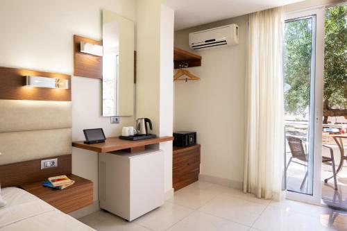 a room with a desk and a window with a table at Elounda Akti Olous (Adults Only) in Elounda