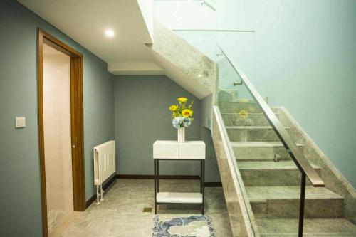 a staircase with a vase of flowers on a table at Guangyao Service Apartment Beijing Ritan in Beijing